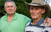 A Portrait of two older Veterans, one with his arm around the other.
