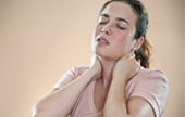 A young woman grips her neck with both hands in pain.