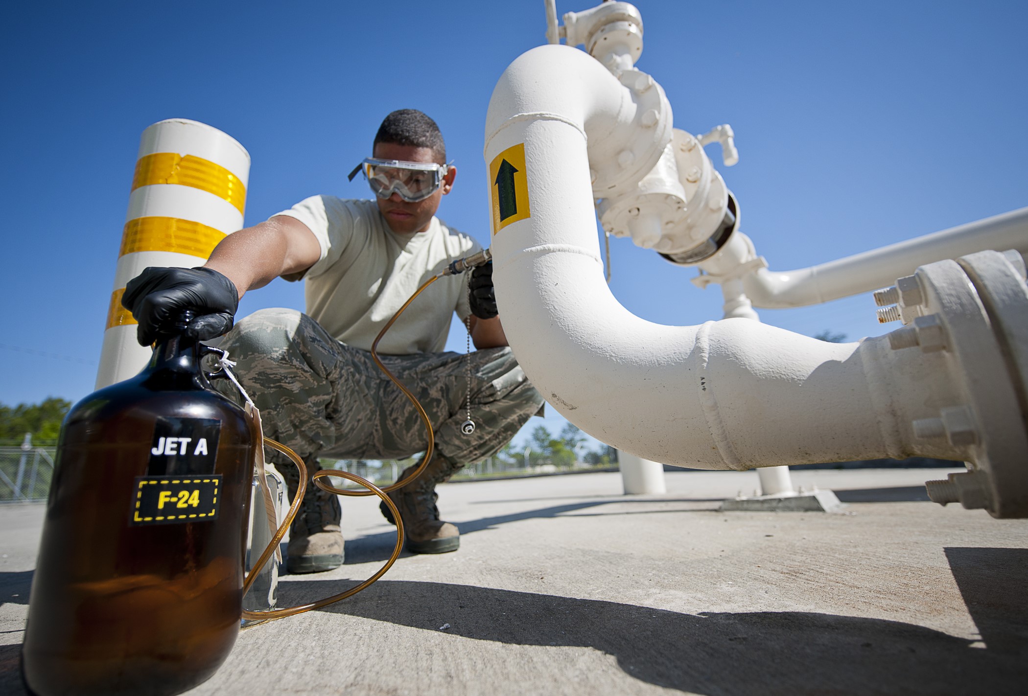 Senior Airman takes a sample of Jet-A fuel from a pipe while the fuel is being offloaded from a truck at Eglin Air Force Base, Fla.