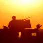 Silhouette of a soldier on a truck in front of the bright sun