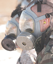 Two servicemembers wearing gas masks