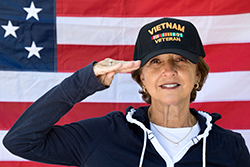 female Vietnam Vet salutes in front of American flag