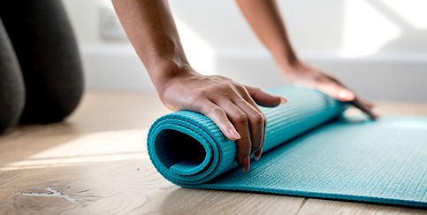 hands rolling up a yoga mat