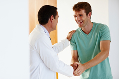 Image of a young male patient shaking a male doctor's hand.