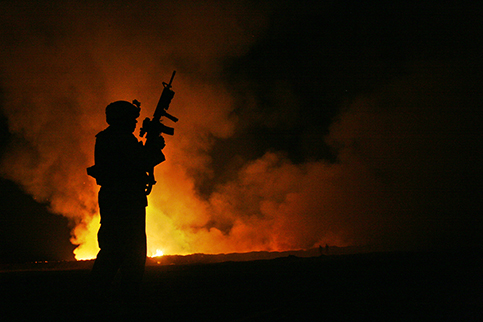 Silhouette of a soldier infront of a cloudy sunset.