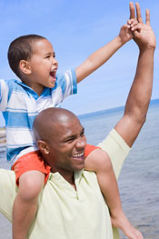 A veteran walking on the beach with his son on his shoulders